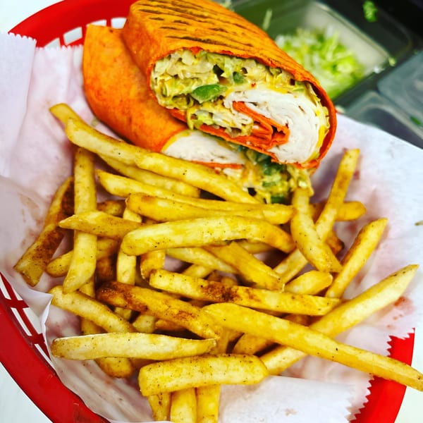 A Delite Cafe and Deli Taylor turkey wrap with fries in a red basket.